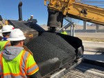 Crew members in hard hats and safety vests beside a paver placing a HiMod asphalt mix