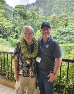 Jon Young wearing the lei presented to him at the Superintendents Conference, standing with a fellow attendee